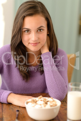 Teenage girl sitting behind table cereal breakfast