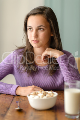 Thoughtful young woman with cereal breakfast table