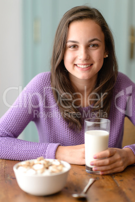 Smiling young woman holding glass of milk