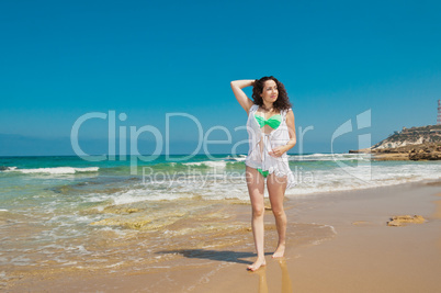 Girl in green bikini walks along the sea