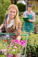 Woman put flowers in shopping cart greenhouse