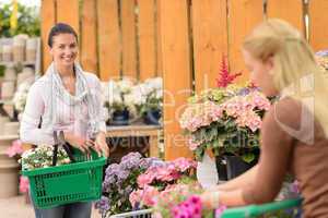 Woman buying flowers shopping basket garden center