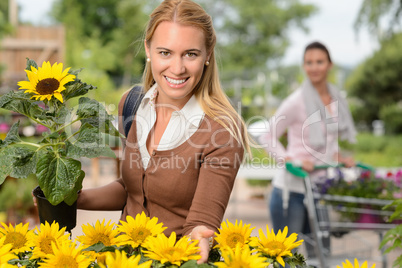 Smiling woman hold potted sunflower garden center