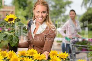 Smiling woman hold potted sunflower garden center