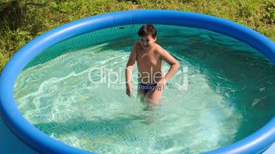 Boy having fun in outdoor pool on a hot summer day