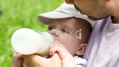 Dad feeding his baby from the bottle outdoor