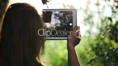 Woman taking pictures of nature with a tablet computer