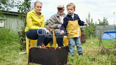 Mother, son and grandpa by fire in the yard