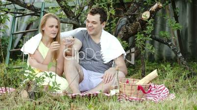 Young couple on picnic drinking wine and talking