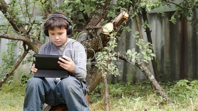 Teenager in earphones using touchpad outdoor