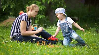 Mother and son playing outdoor on the green lawn