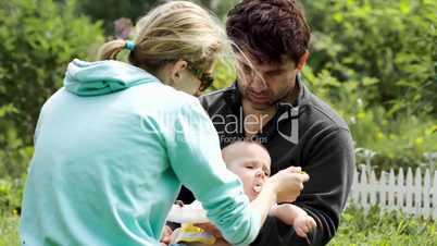 Young parents feeding a baby boy outdoor