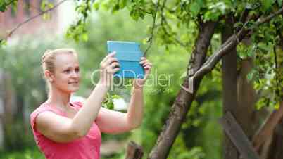 Young woman taking pictures of nature scenes with her pad