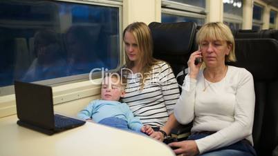 Son with mother watching video on laptop, grandma talking phone