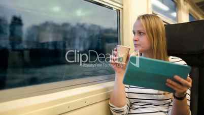 Woman with touchpad and tea in train