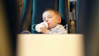 Boy in the train drinking milk from bottle