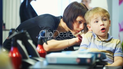 Little child getting his hair cut at the hairdressing saloon