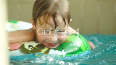 Cute child having fun swimming with rubber ring in the pool