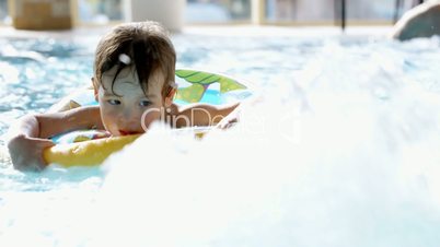 Little boy swimming in the pool with rubber ring