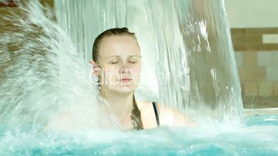 Woman under water shower in the swimming pool
