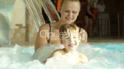 Mother holding son splashing in the rough water of pool
