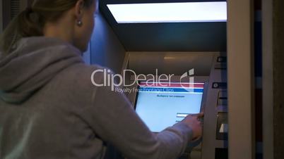 Woman using ATM outdoor in the evening