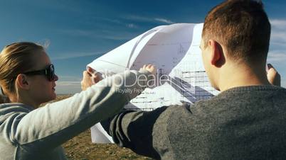 Young architects examining open territory using their plans