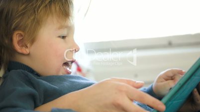 Boy in the train using touchpad held by mother