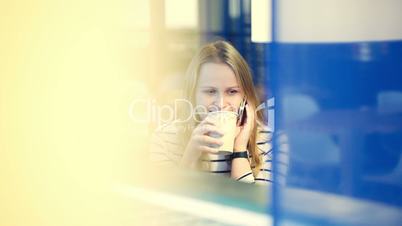 Woman in the cafe having a phone talk while drinking tea