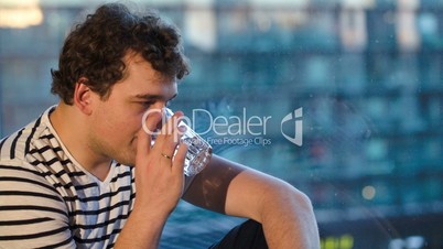 Happy man sitting by the window with a glass of water
