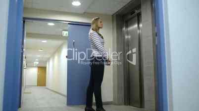 Young woman calling and waiting for elevator