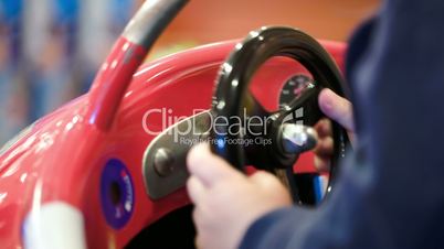 Child turning steering wheel of a toy car