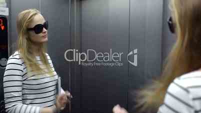 Young woman in the lift primping and make funny face