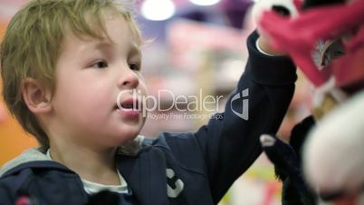 Little child choosing soft toys in the shop