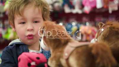 Little boy looking at the toy horses in shop