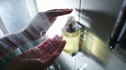 Female hands pushing container with liquid soap while taking a shower
