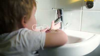 Boy washing hands with soft soap and turning off water