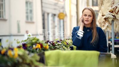Young woman talking on the phone in outdoor cafe