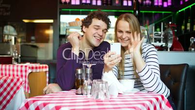 Young couple in cafe having a video chat on smartphone