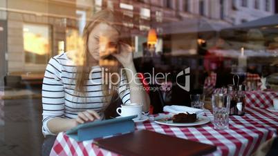 Woman in cafe using tablet PC and eating dessert
