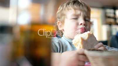 Cute boy eating a bun in cafe