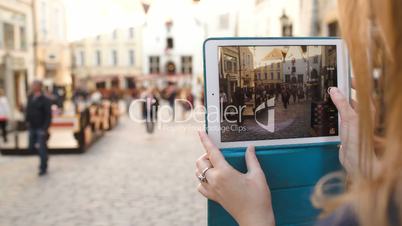 Woman with tablet making video of street in Tallin and then watching it