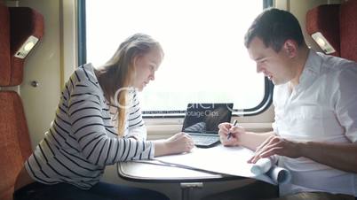 Man and woman discussing drawing during business trip in the train