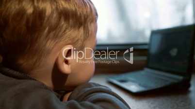 Little boy watching video on laptop in the train