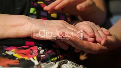 Young woman stroking her grandmothers hands