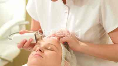 Woman getting ultrasonic face cleaning at beauty spa