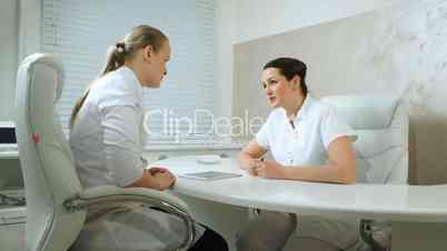 Two cosmeticians talking in the office room