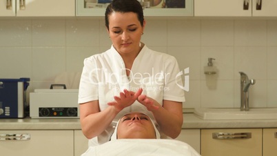 Massage therapist making facial massage at beauty spa