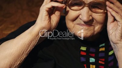 Elderly woman putting on glasses