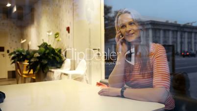 Evening phone talk of a young woman in cafe